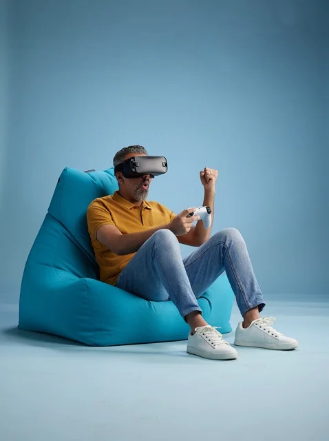 Saudi Man Playing VR Games on Bean Bag Blue Background