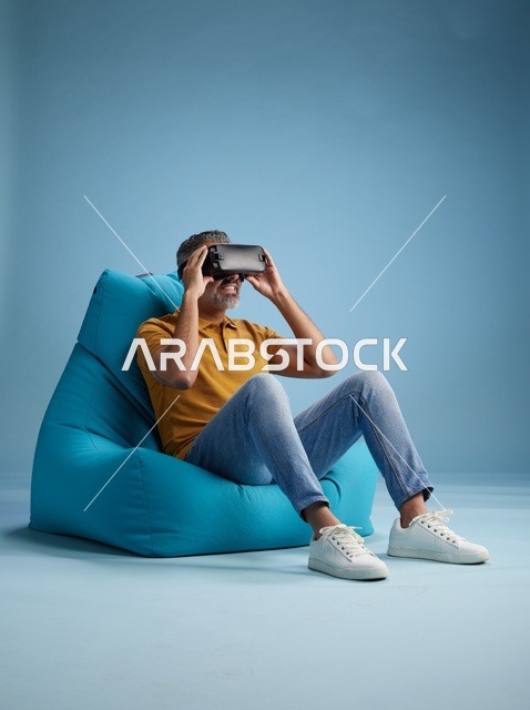رجل سعودي يستخدم نظارة واقع افتراضي على كرسي بين باق