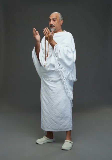 رجل سعودي بملابس الإحرام يدعو بالمسبحة