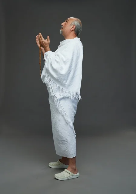 Saudi Man in Ihram Praying on Grey Background
