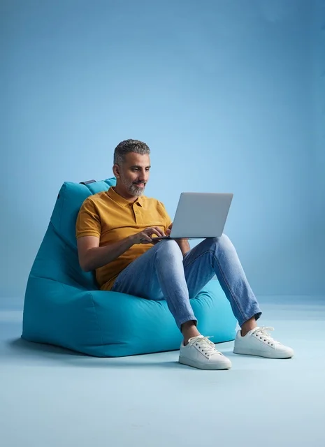 Saudi Man Working on Laptop on Bean Bag Studio Background