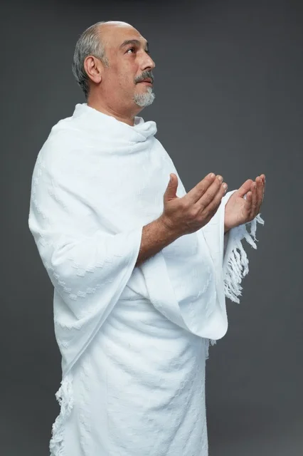 Saudi Man in White Ihram Praying on Grey Background