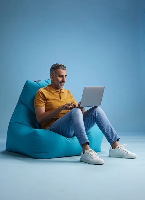 Saudi Man Working on Laptop While Sitting on Blue Bean Bag
