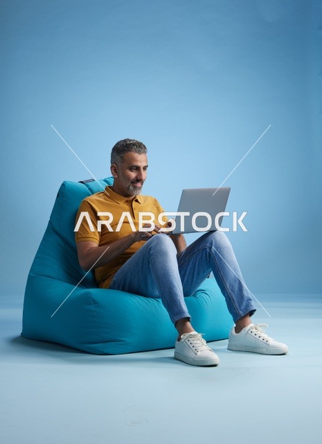 رجل سعودي يعمل على اللابتوب جالساً على بين باق