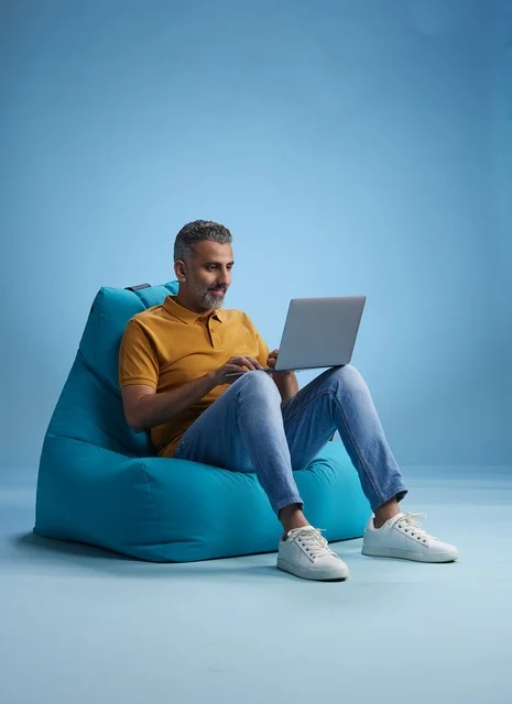 رجل سعودي يعمل على اللابتوب على كرسي بين باق