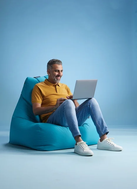 رجل سعودي يعمل على اللابتوب جالسا على كرسي بين باج