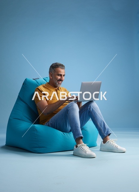 رجل سعودي يعمل على اللابتوب على كرسي بين باق