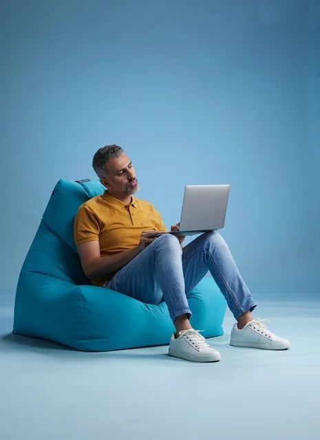 Saudi Man Working on Laptop on Blue Bean Bag Chair