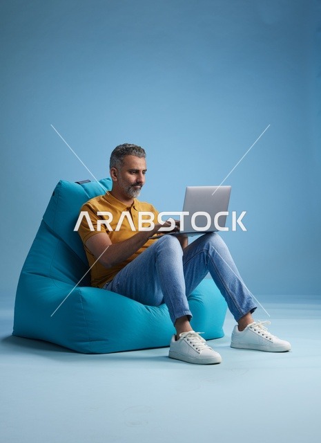 رجل سعودي يعمل على اللابتوب جالساً على بين باج
