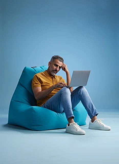 Saudi Man Working on Laptop in Blue Bean Bag Chair