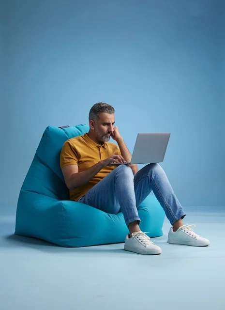 Saudi Man Working on Laptop in Turquoise Bean Bag Chair