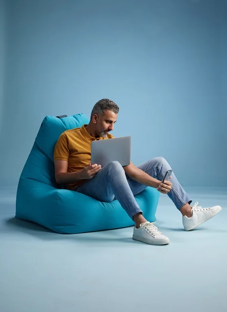 رجل سعودي يعمل على اللابتوب على كرسي بين باق