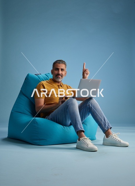 رجل سعودي يعمل على لابتوب على كرسي بين باق