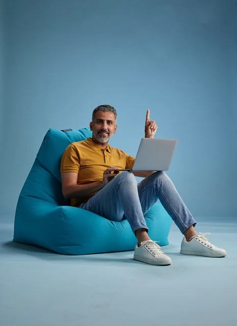 رجل سعودي يعمل على لابتوب على كرسي بين باق