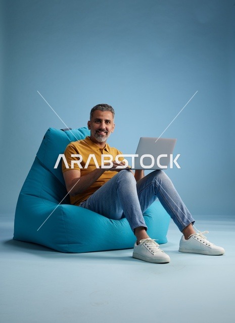 رجل سعودي يستخدم اللابتوب على كرسي بين باق