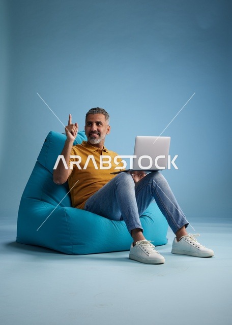 رجل سعودي يعمل على لابتوب جالساً على كرسي بين باق