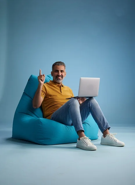 Saudi Man with Laptop Sitting on Bean Bag Chair Studio Portrait