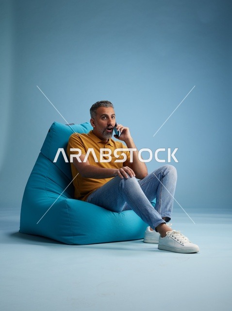رجل سعودي يتحدث بالهاتف على كرسي بين باق