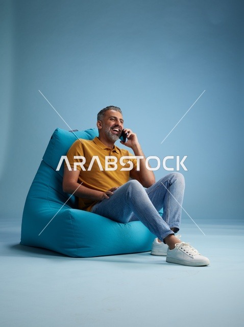 رجل سعودي يتحدث بالهاتف على كرسي بين باق