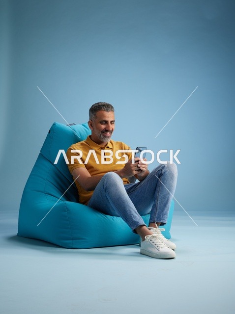 Saudi Man Using Smartphone on Blue Bean Bag