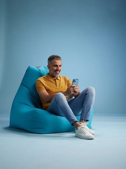 Saudi Man Using Smartphone on Blue Bean Bag