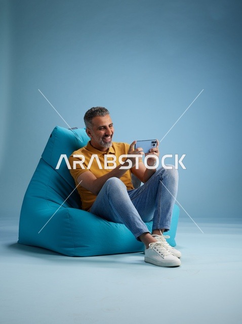 رجل سعودي يستخدم الهاتف الذكي على كرسي بين باج