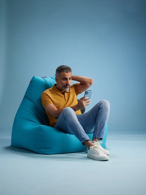 Saudi Man with Smartphone Sitting on Blue Bean Bag