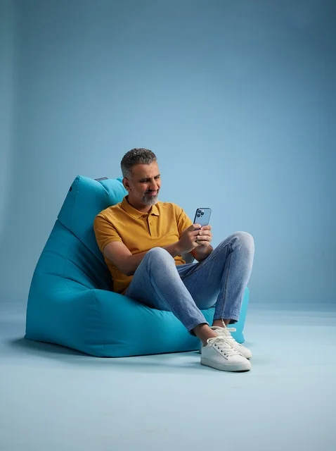 رجل سعودي يستخدم الهاتف الذكي على كرسي بين باق