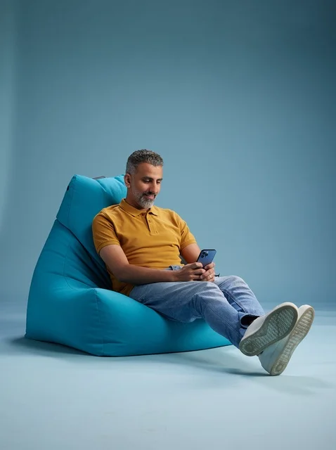 Saudi Man Using Smartphone on Blue Bean Bag Chair