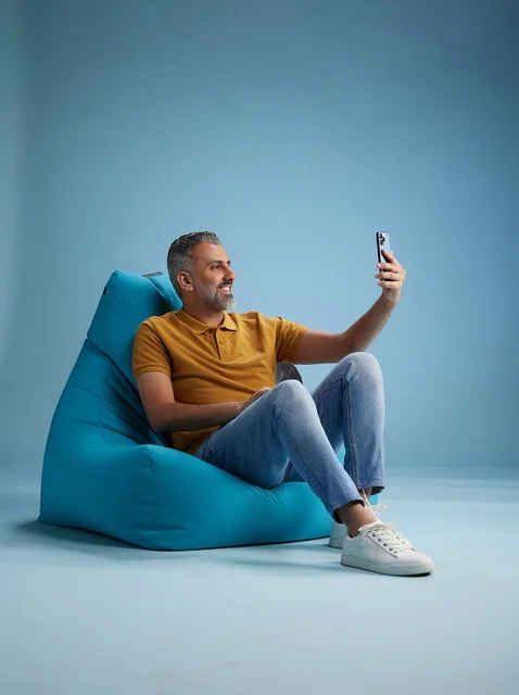 Saudi Man Taking Selfie on Bean Bag Blue Background
