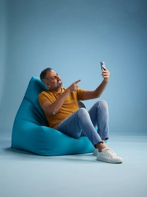 رجل سعودي على كرسي بين باق يلتقط سيلفي بالهاتف