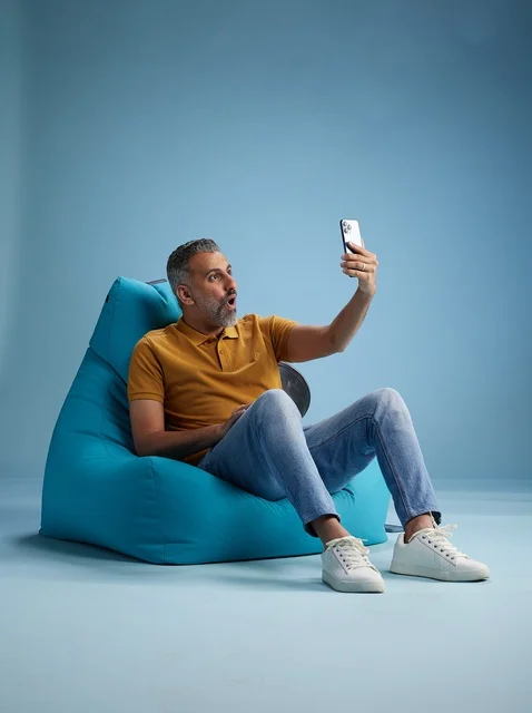 Saudi Man on Blue Bean Bag Taking Smartphone Selfie