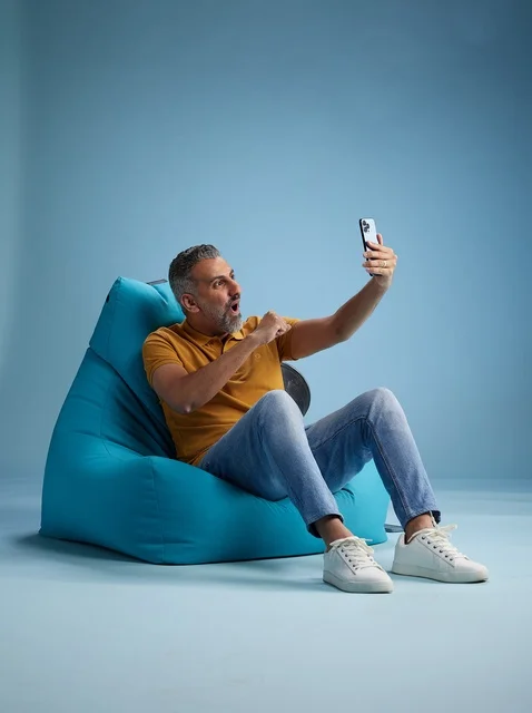 Saudi Man Taking Selfie on Blue Bean Bag in Studio Saudi Man Taking Selfie on Blue Bean Bag in Studio