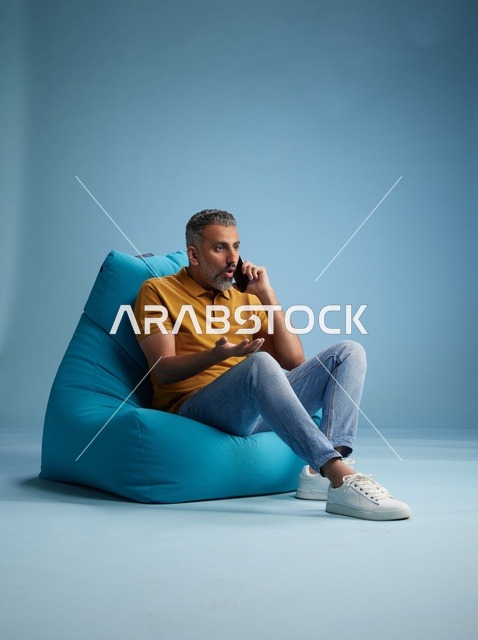 رجل سعودي يتحدث بالهاتف على كرسي بين باج