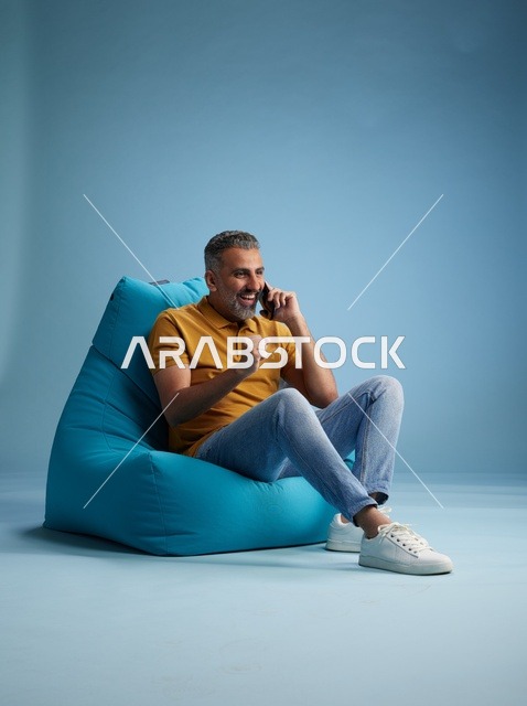 رجل سعودي يتحدث بالهاتف على كرسي بين باق