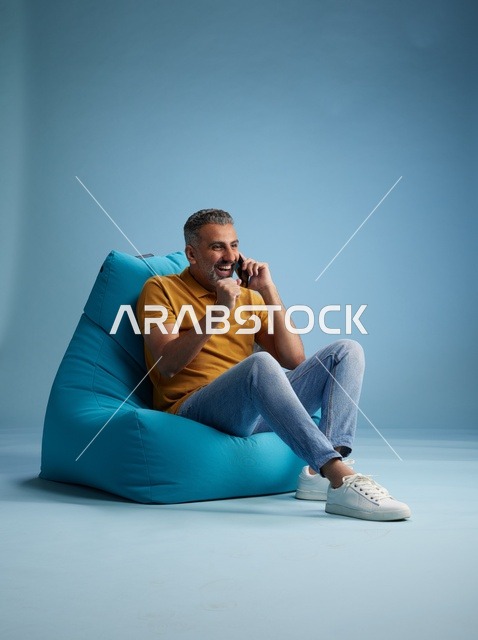 رجل سعودي يتحدث بالهاتف على كرسي بين باق