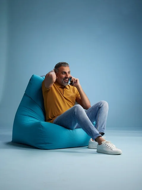 رجل سعودي يتحدث بالهاتف جالساً على كرسي بين باج