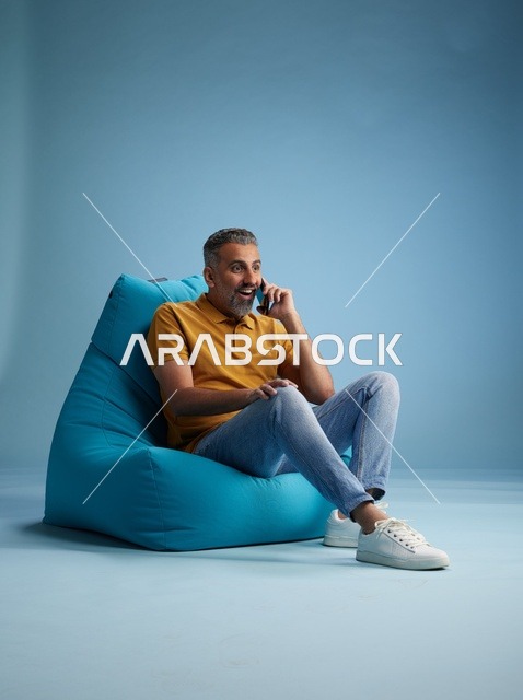 رجل سعودي يتحدث بالهاتف جالساً على بين باج
