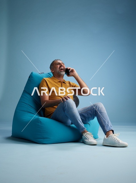 رجل سعودي يتحدث بالهاتف على كرسي بين باج