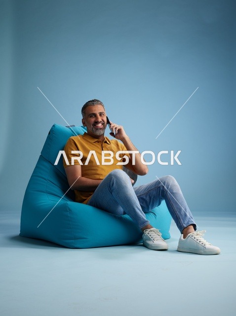 رجل سعودي يتحدث بالهاتف المحمول جالساً على بين باج