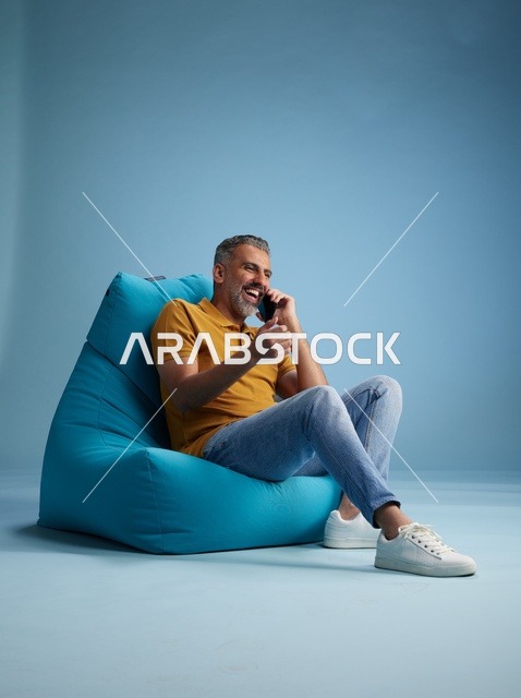 رجل سعودي يتحدث بالهاتف على كرسي بين باج في استوديو