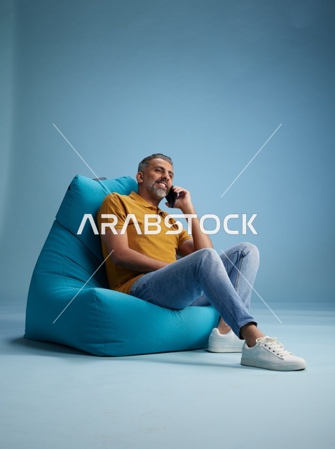 رجل سعودي يتحدث بالهاتف على كرسي بين باج