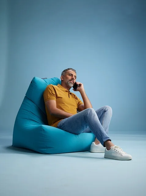 رجل سعودي يتحدث بالهاتف جالسًا على كرسي بين باق