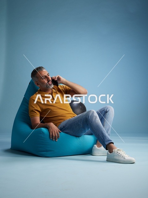 رجل سعودي يتحدث بالهاتف على كرسي بين باق
