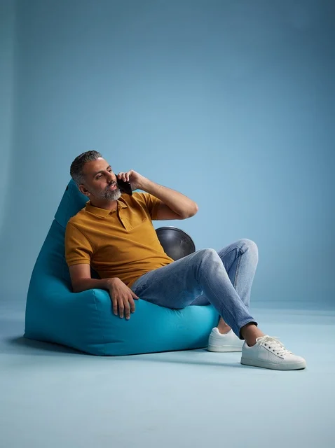 رجل سعودي يتحدث بالهاتف على كرسي بين باق