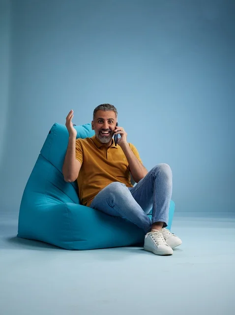 رجل سعودي يتحدث بالهاتف جالساً على كرسي بين باج