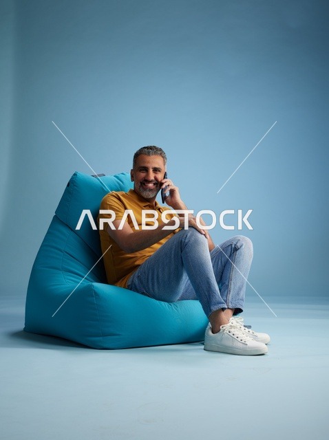 رجل سعودي على كرسي بين باق يتحدث عبر الهاتف الذكي