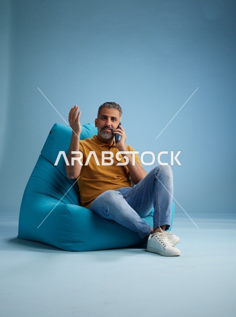 رجل سعودي يتحدث بالهاتف جالساً على كرسي بين باج