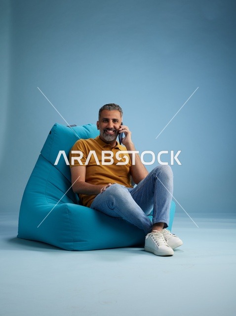 Saudi Man Talking on Mobile Phone Sitting on Blue Bean Bag