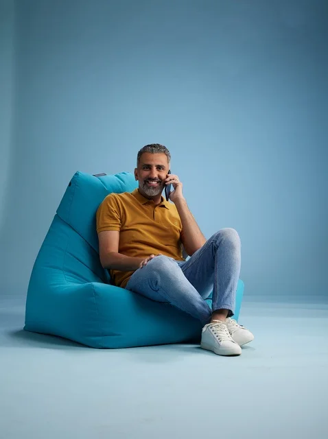 رجل سعودي يتحدث عبر الجوال جالساً على كرسي بين باق